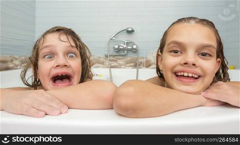 Two sisters bathe in the bath and make fun faces