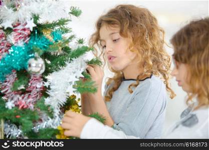 Two sisters decorating a Christmas tree