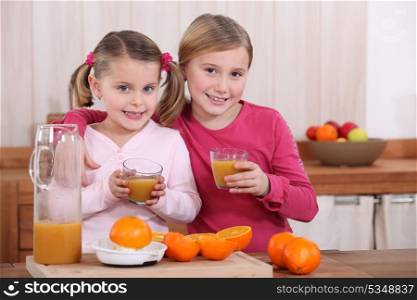 Two sisters drinking orange juice in kitchen