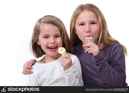Two sisters eating lollipops.