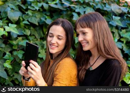 Two sisters enjoying of a day in the park with a mobile