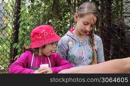 two sisters happy play cards with other children, sitting at table in yard