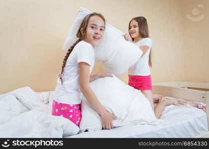 Two sisters having pillow fight on bed