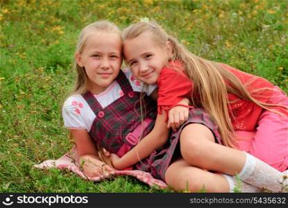 Two sisters hug one another outdoors, happy family