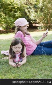 Two sisters listening to MP3 players in a park