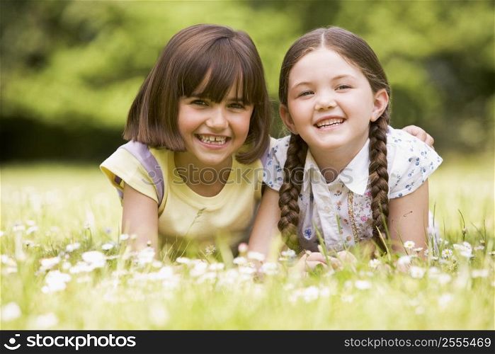 Two sisters lying outdoors smiling