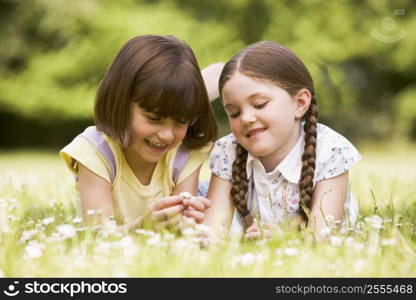 Two sisters lying outdoors with flower smiling