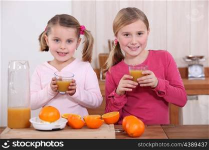 Two sisters making orange juice