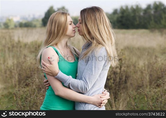 Two sisters or female friends in an intimate embrace standing close together looking deeply into each other eyes
