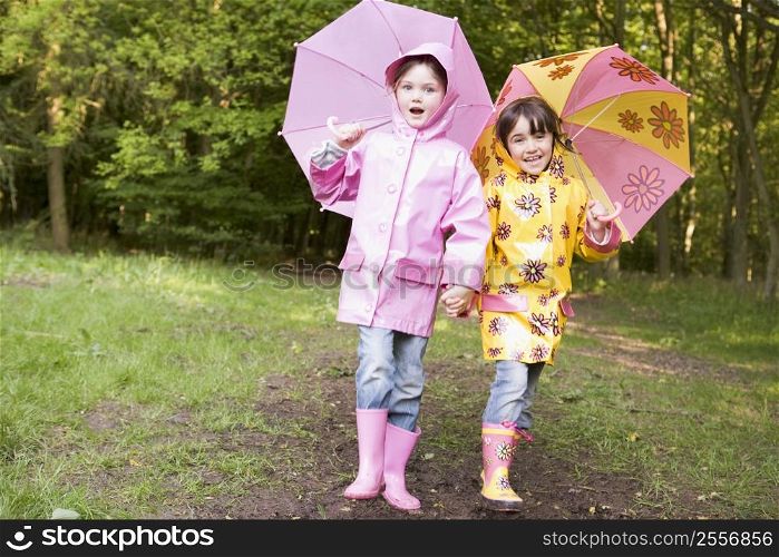 Two sisters outdoors with umbrellas smiling
