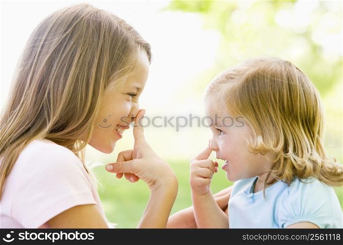Two sisters playing outdoors and smiling