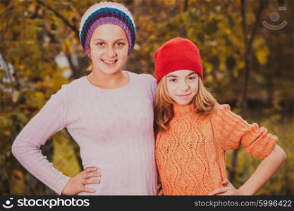 Two sisters playing with autumn leaves and smiling. Sisters playing with leaves