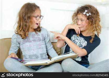 Two sisters reading a book