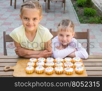 Two sisters sitting at a table on which are freshly baked Easter cupcakes