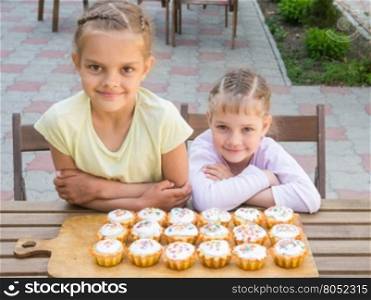 Two sisters sitting at a table on which are freshly baked Easter cupcakes