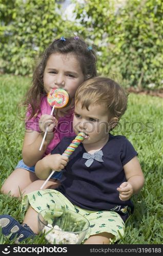 Two sisters sitting in a park and eating candies