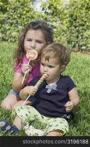 Two sisters sitting in a park and eating candies