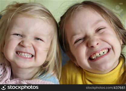 two sisters smiling and grimacing looking at the camera