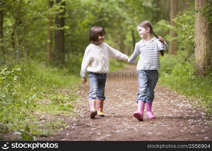 Two sisters walking on path holding hands smiling