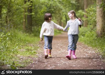 Two sisters walking on path holding hands smiling