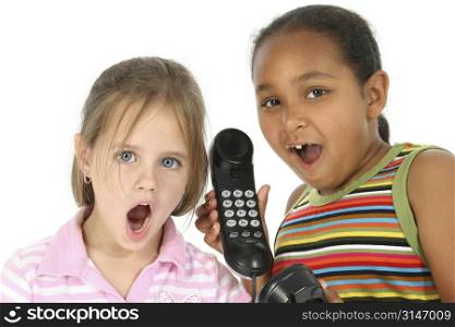 Two six year girls on the telephone. Surprised expressions.