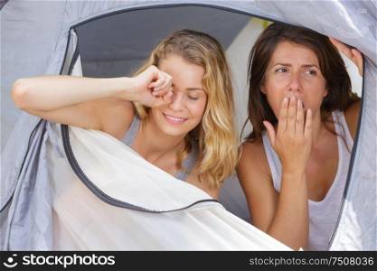 two sleepy young ladies waking up in their tent