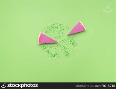 Two slices of pink chocolate pie and grease traces, on a green background. Ruby chocolate pie leftovers. Pie chart concept. Christmas pink dessert.