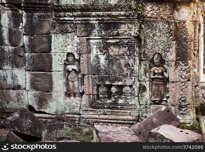 Two small carvings of women flank a fake stone window in a well at the ancient Preah Khan temple near Angkor Wat.&#xA;
