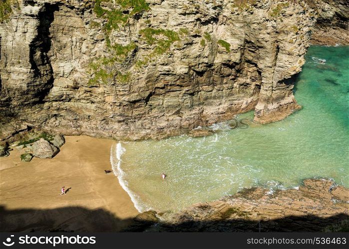 Two small girls and dog playing on beach and in sea near Tintagel, Cornwall, England, UK. Children playing on beach near Tintagel in Cornwall