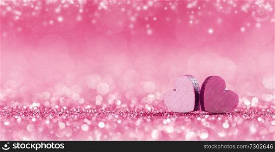 Two small handmade pink wooden hearts on bright lights bokeh background. Pink hearts on bokeh background