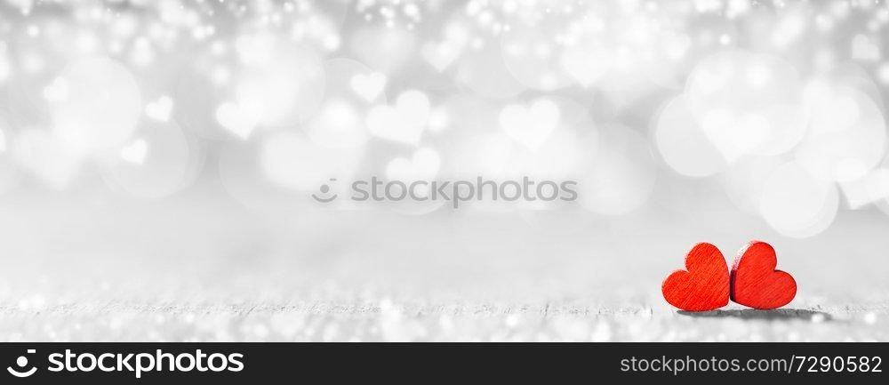 Two small handmade red wooden hearts on bright heart lights bokeh background. Red hearts on bokeh background