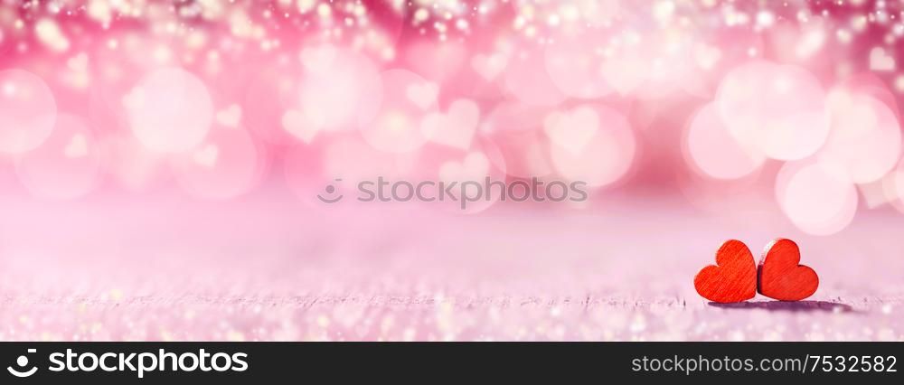 Two small handmade red wooden hearts on bright pink lights bokeh background Valentines day card. Two hearts on bokeh background