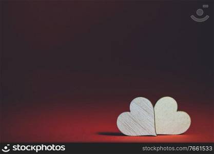 Two small handmade wooden hearts on dark red background Valentines day card. Two hearts on dark background