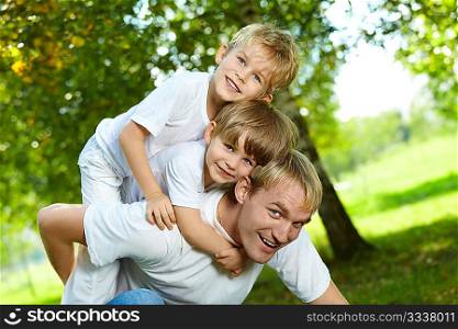 Two small sons piggyback on the daddy