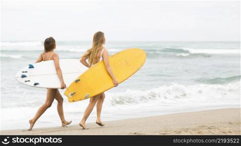 two smiley friends running beach with surfboards
