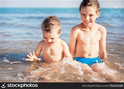 two smiling boys sitting on beach. smiling boys sitting on beach