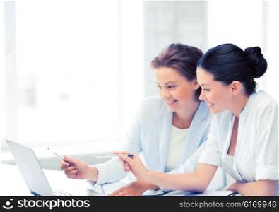 two smiling businesswomen working with laptop in office. businesswomen working with laptop in office