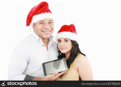 Two smiling couple holding tablet touch pad with hat santa