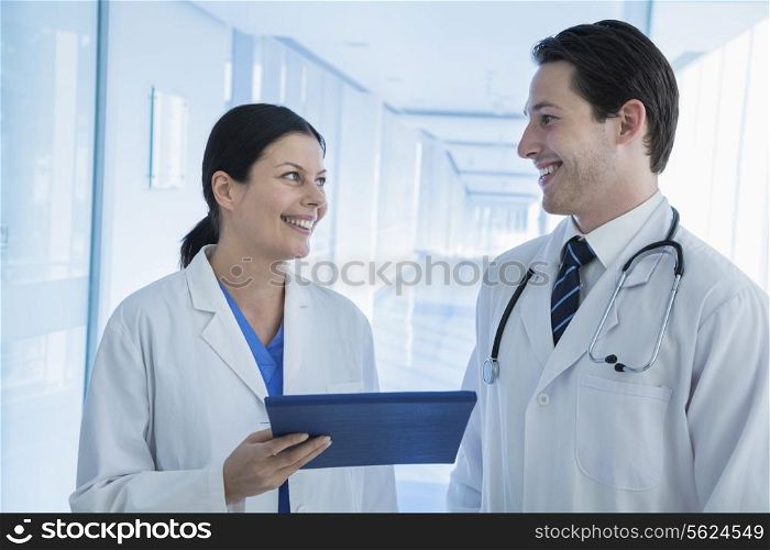 Two smiling doctors looking and holding a medical record in the hospital