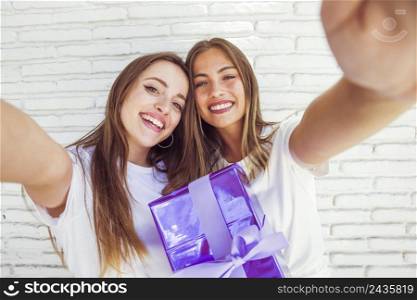 two smiling female friends with birthday gift