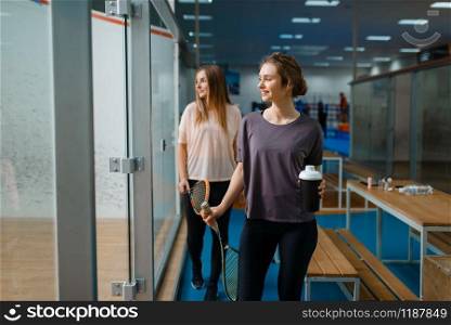 Two smiling female squash players in gym. Youth on training, active sport hobby, fitness workout for healthy lifestyle. Two smiling female squash players in gym