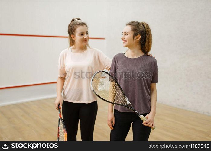 Two smiling female squash players poses in locker room. Youth on training, active sport hobby, fitness workout for healthy lifestyle. Two female squash players poses in locker room