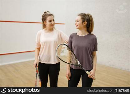 Two smiling female squash players poses in locker room. Youth on training, active sport hobby, fitness workout for healthy lifestyle. Two female squash players poses in locker room
