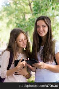two smiling girls students with the tablets outdoors
