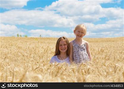 two smiling sisters sitting at the wheat field