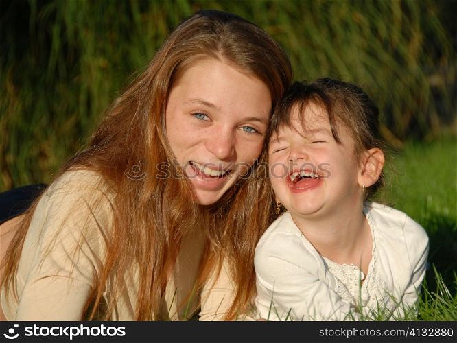 two smiling sisters: teenager and little girl