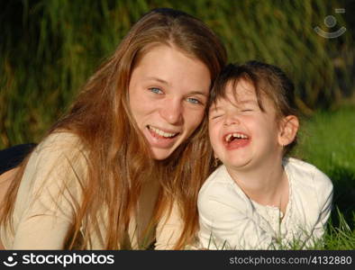 two smiling sisters: teenager and little girl