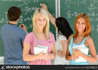 Two smiling student girls in math class chalkboard in background