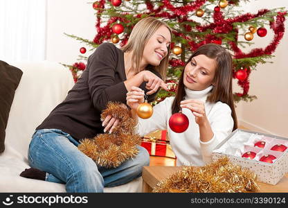 Two smiling women with Christmas decoration, chains and balls