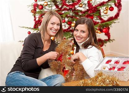 Two smiling women with Christmas decoration, chains and balls
